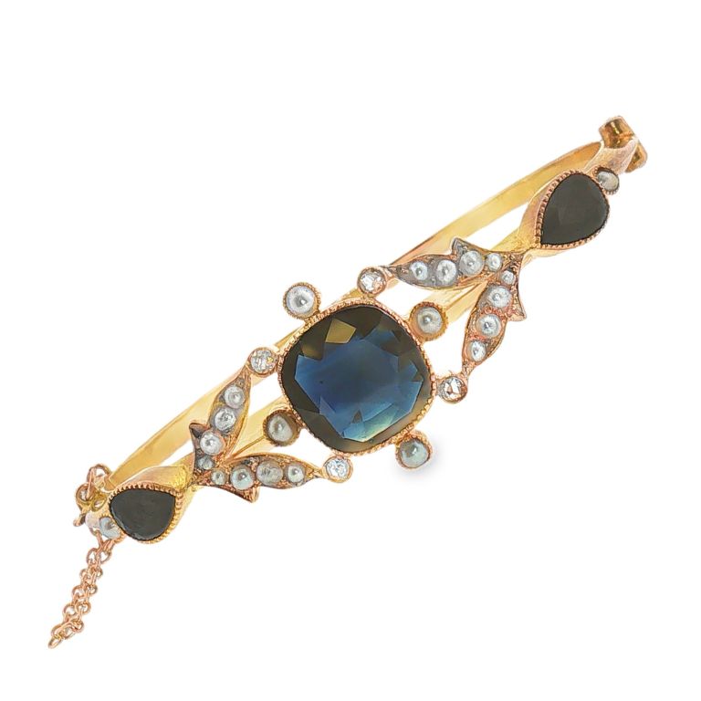 10k yellow gold hinged bracelet set with 1 cushion cut blue sapphire and 2 pear shaped blue sapphires and 22 round pearls and 4 round cut diamonds.